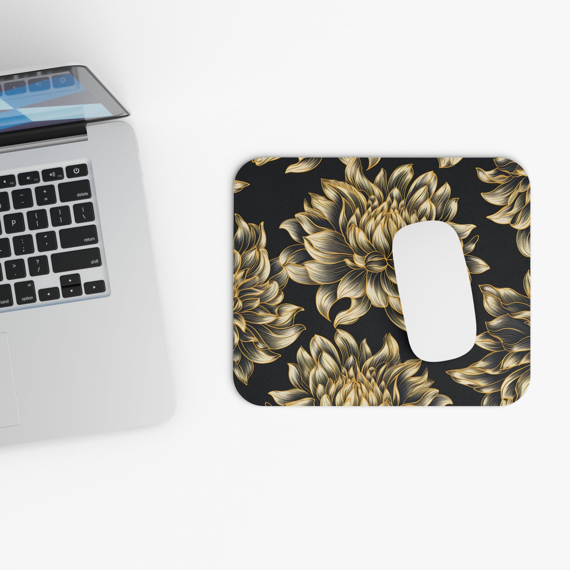 Mousepad with gold floral pattern next to laptop keyboard.