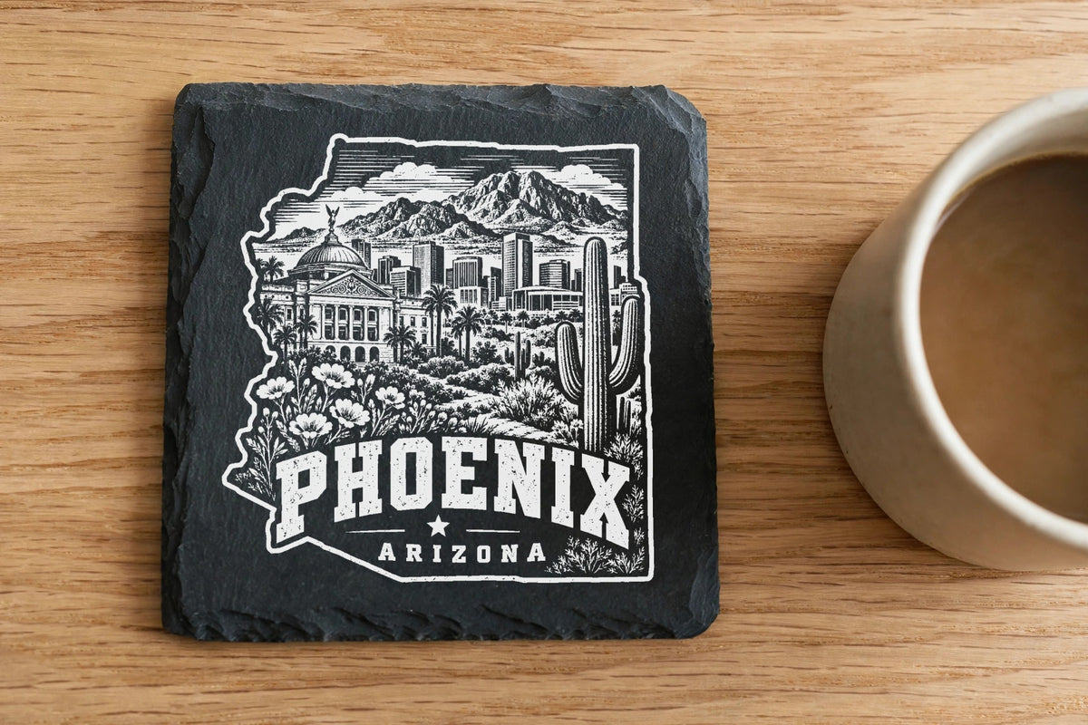 Black slate coaster featuring a white laser-engraved Phoenix, Arizona skyline design next to a coffee mug.