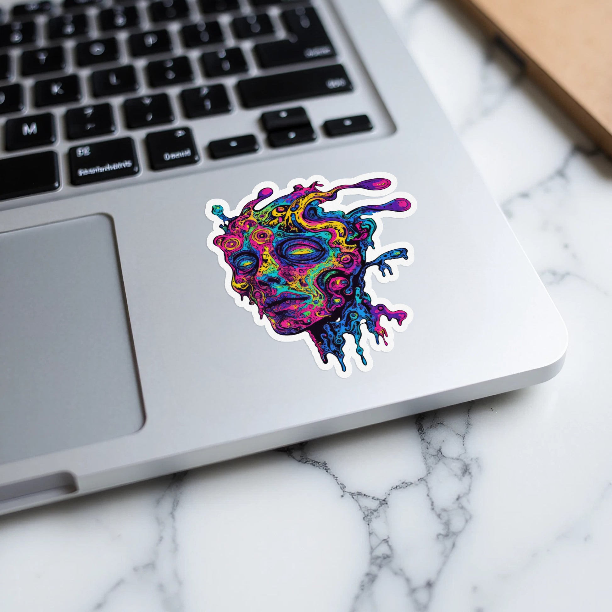 Colorful, melting abstract face sticker on a laptop.