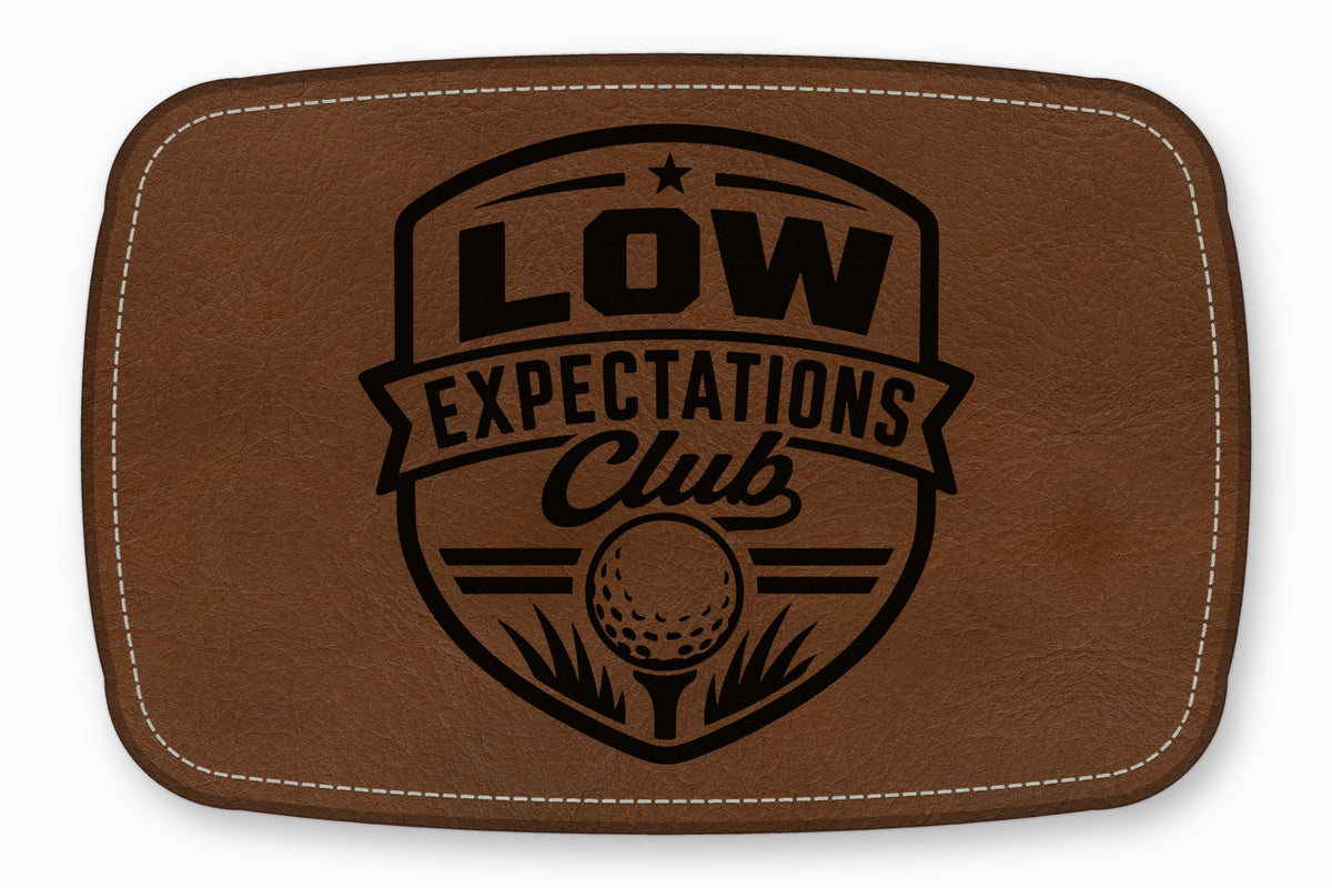 Brown leather patch with white stitching and a black golf crest design reading Low Expectations Club.