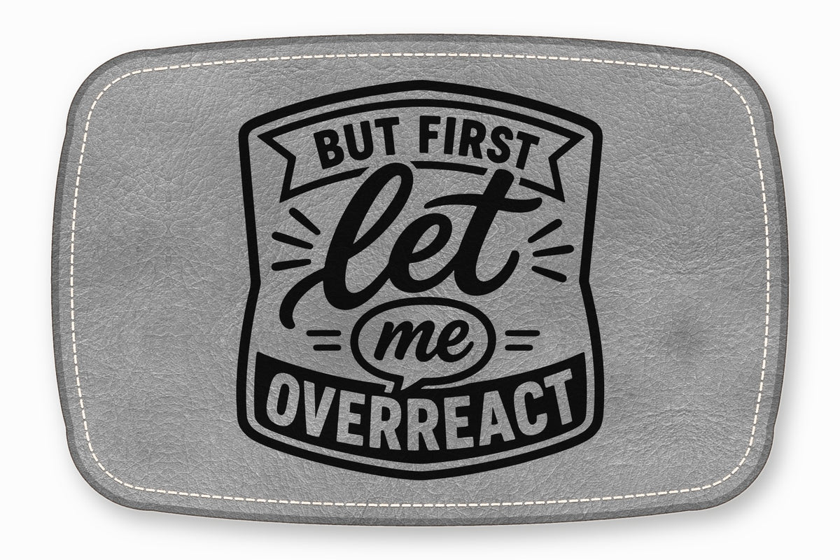 A gray faux leather patch with white stitched edges and black text reading But first let me overreact.