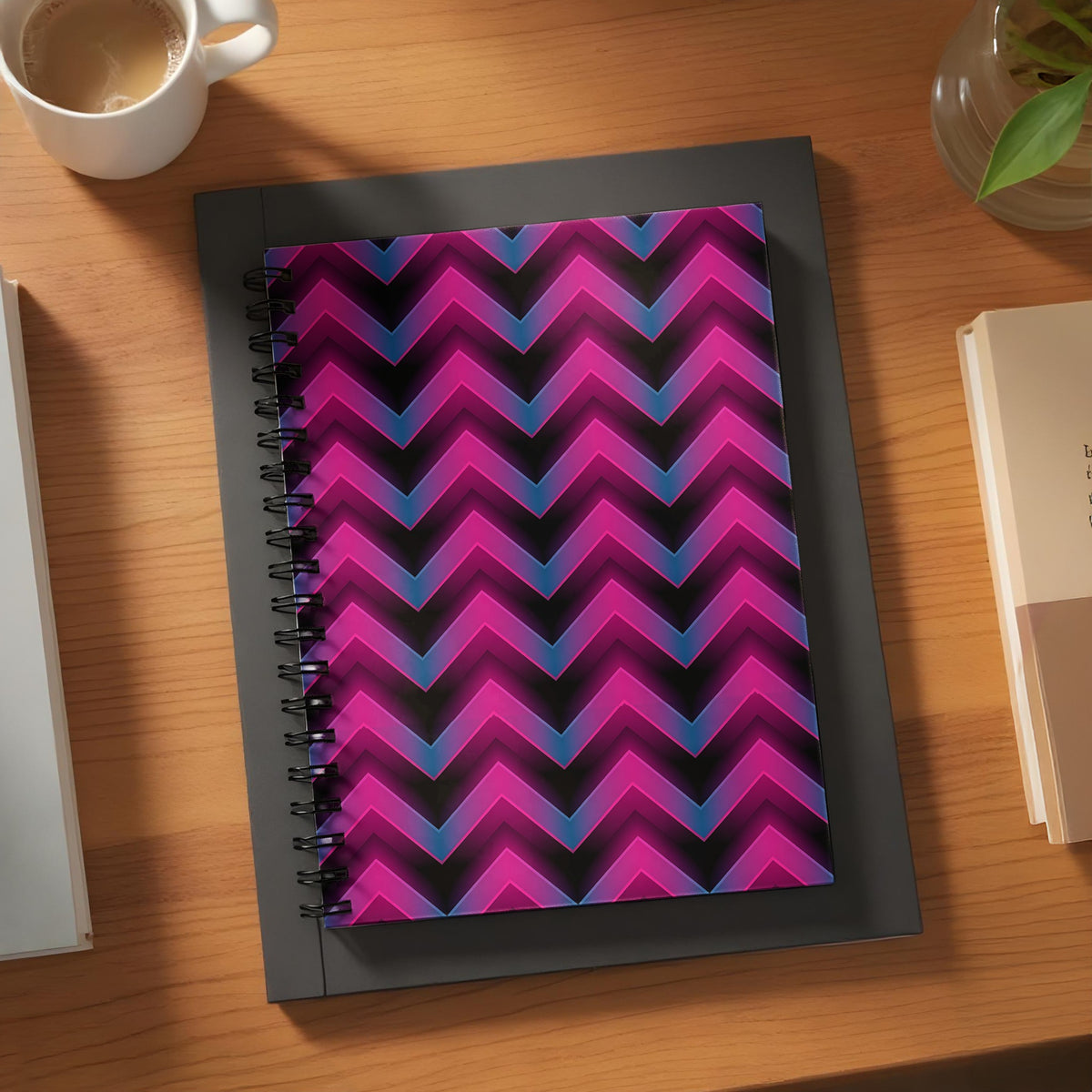 Spiral bound notebook with a magenta and blue chevron pattern on a black background.