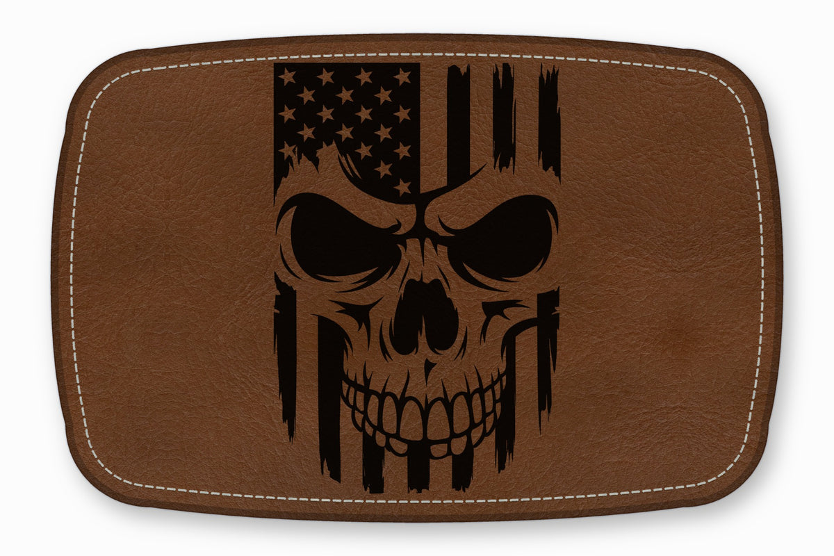 Brown rectangular leather patch with white stitched borders and a black engraved American flag skull design.