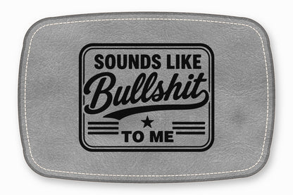 A rectangular grey leather patch with white stitching featuring the black text Sounds Like Bullshit To Me.