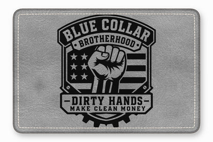 A gray leather rectangle with rounded corners features a black embossed design depicting a raised fist, American flag elements, and text reading Blue Collar Brotherhood, Dirty Hands, Make Clean Money.