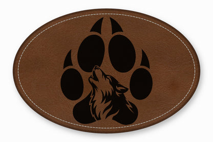 Oval brown leather patch with white stitching and a black paw print containing a howling wolf.