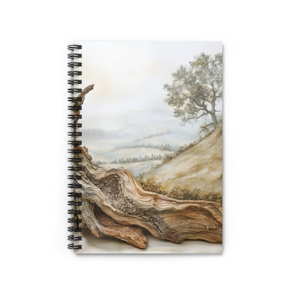 Notebook with a painting of a tree and rolling hills, foreground shows textured wood.