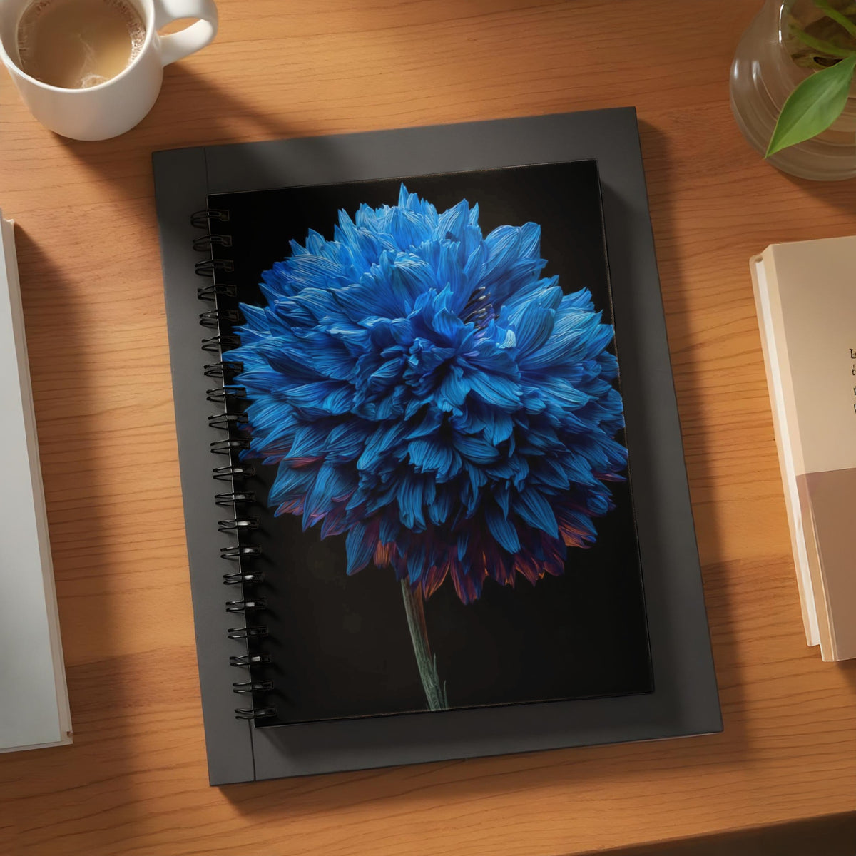 Black spiral notebook featuring a vibrant blue chrysanthemum on a dark background.