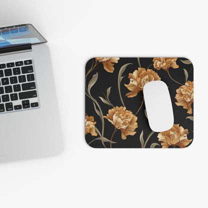 Mousepad with a floral pattern of orange peonies on a dark background, beside a laptop.