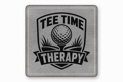 A square grey faux leather patch with white stitched borders and a black golf-themed design reading Tee Time Therapy.