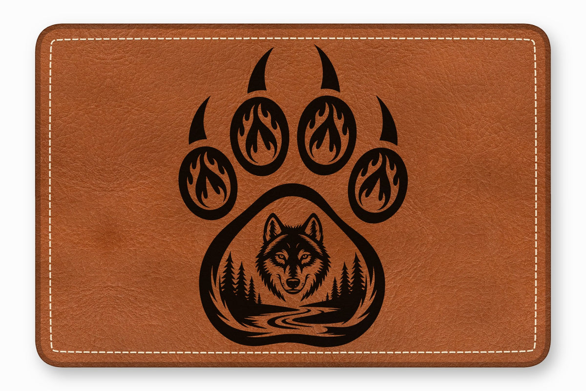 Brown leather patch featuring a black engraved bear paw print enclosing a forest landscape and wolf face.