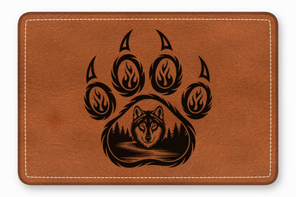 Brown leather patch with rounded corners and white stitching, featuring a black wolf in a forest paw print graphic.