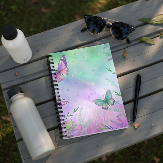 Spiral notebook with watercolor butterflies and greenery on purple and green background.