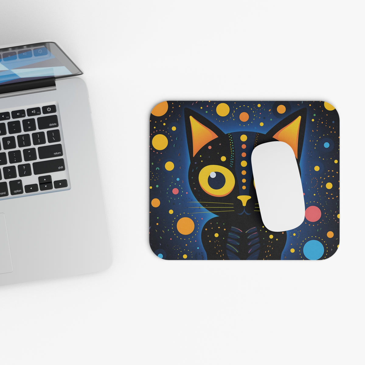 Abstract black cat with colorful dots on a dark blue mousepad next to a laptop.