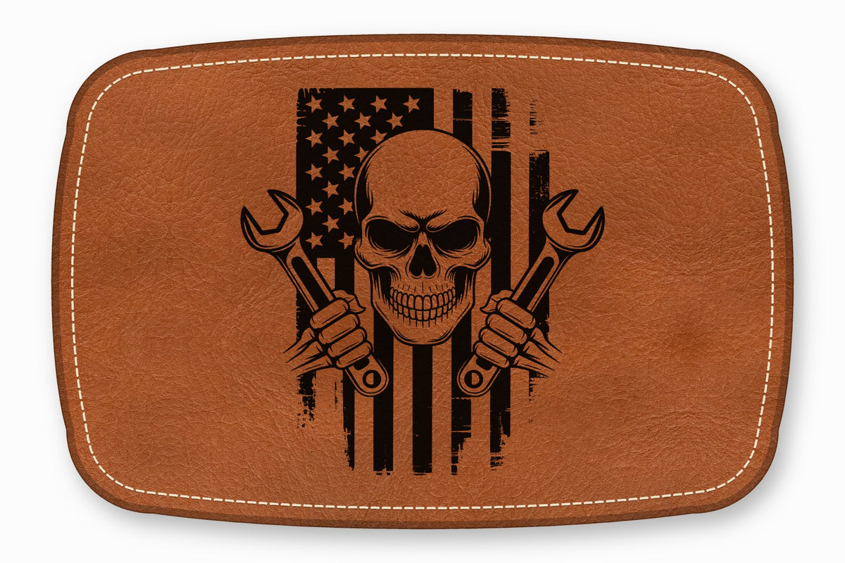 Brown leather patch featuring a black graphic of a skull holding two crossed wrenches over a distressed American flag.