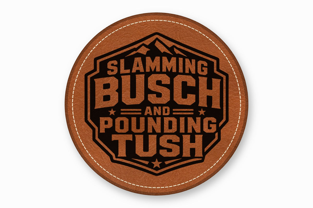A round brown leather coaster features a black-and-tan mountain emblem with the text Slamming Busch and Pounding Tush.