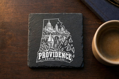 Square slate coaster engraved with a white Providence, Rhode Island city map and skyline on a wooden table.