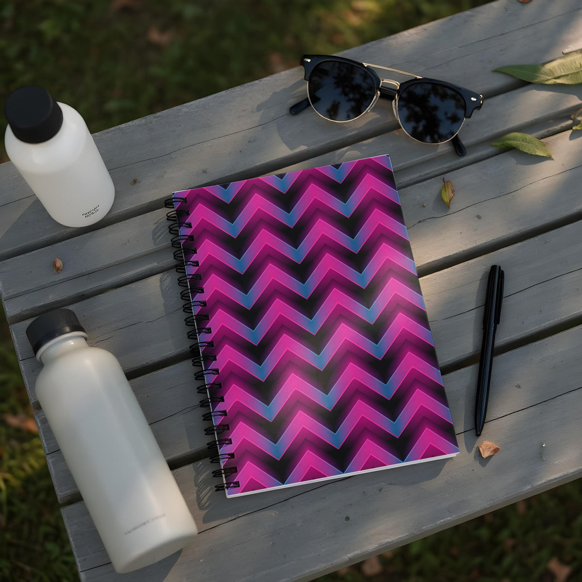 Spiral-bound notebook with pink and blue chevron pattern on a wooden table.