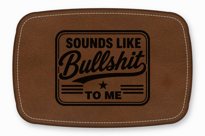 Brown leather patch with white stitching and the engraved text Sounds Like Bullshit To Me.