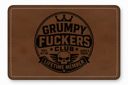 Brown leather patch with rounded corners, white stitching, and a black skull emblem and text.