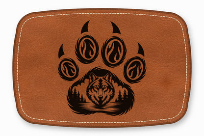 Brown leather patch with rounded corners, white stitching, and a black laser-engraved wolf in a paw print design.