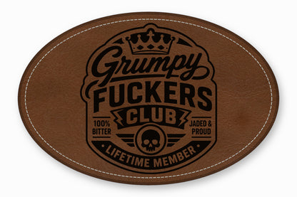 Brown oval leather patch featuring a black stamped Grumpy Fuckers Club logo with a skull and crown.