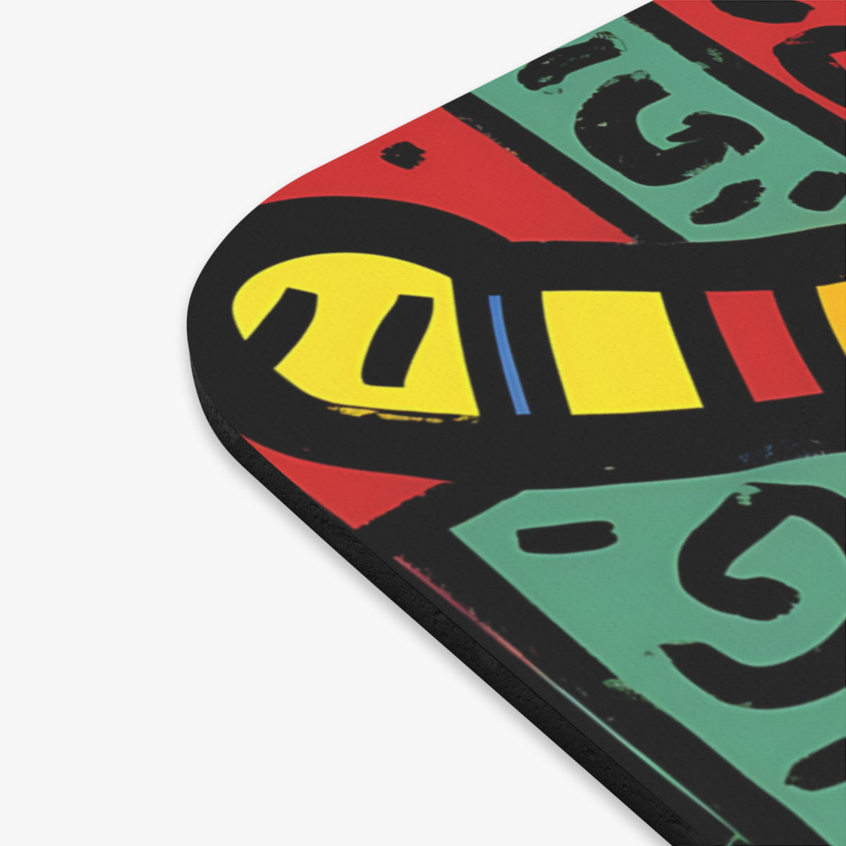 A close-up of a mousepad with rounded corners featuring bold abstract shapes in black, yellow, red, and green.