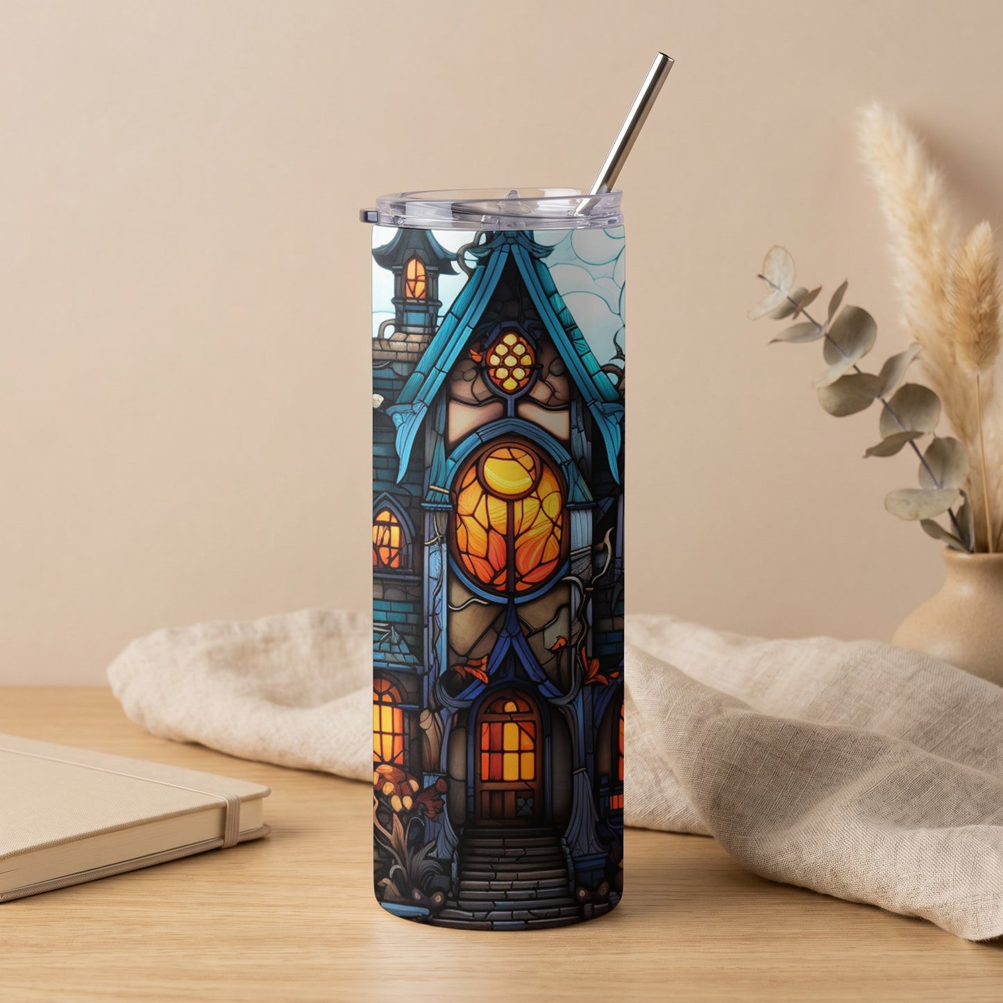 Tumbler with stained glass haunted house design, metal straw, and clear lid.
