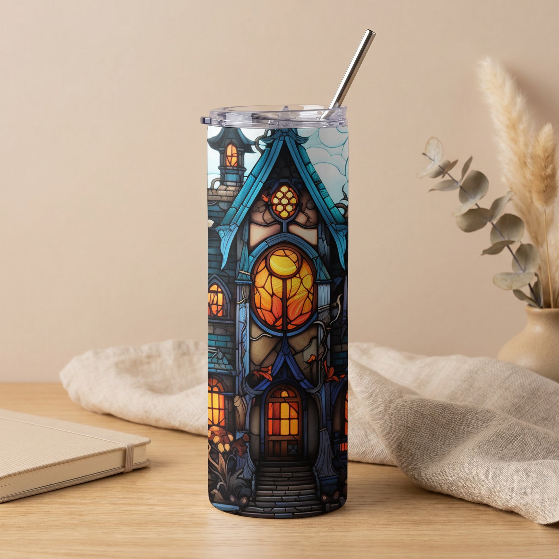 Tumbler with stained glass haunted house design, metal straw, and clear lid.