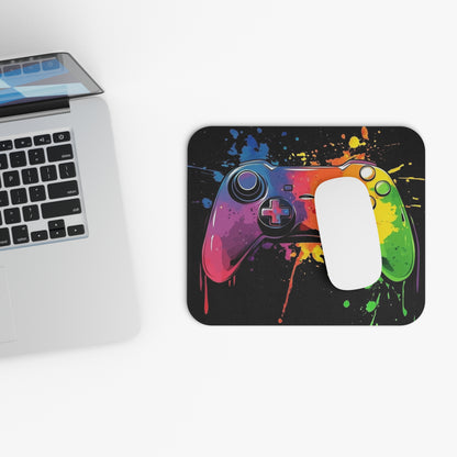 Mousepad with colorful splatter art of a video game controller, next to a laptop.