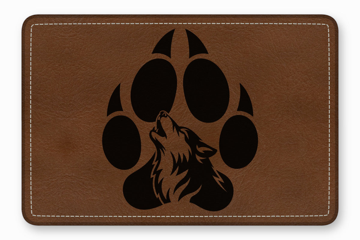 Brown leather patch with rounded corners featuring a black silhouette of a wolf howling inside a paw print.