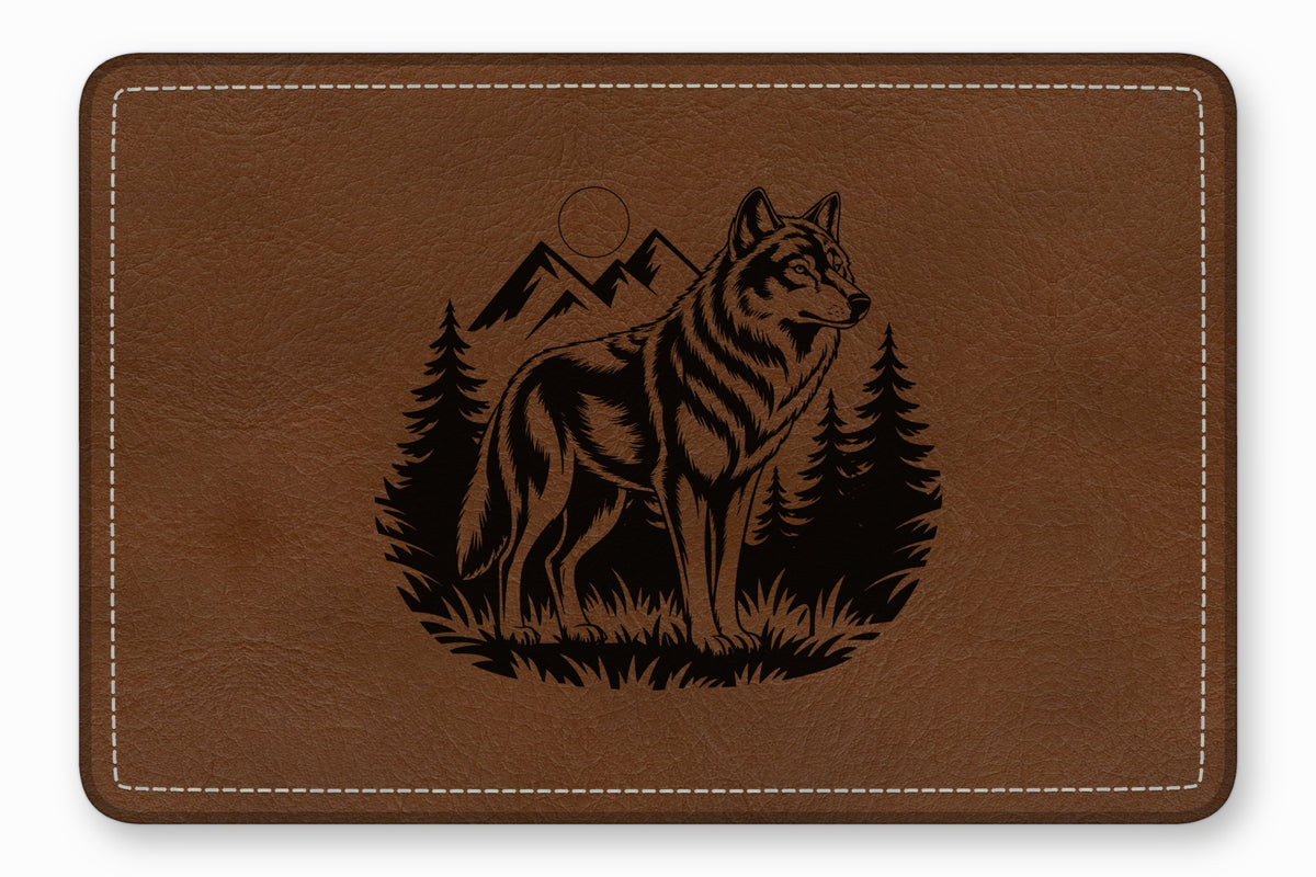 Brown leather desk mat featuring a laser-engraved design of a wolf standing before mountains and pine trees.