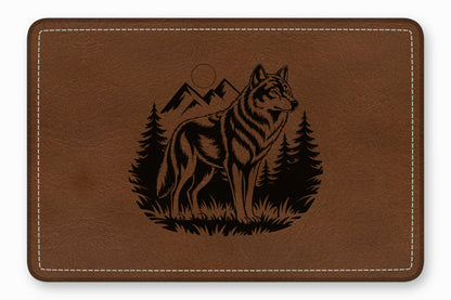 Brown leather desk mat featuring a laser-engraved design of a wolf standing before mountains and pine trees.