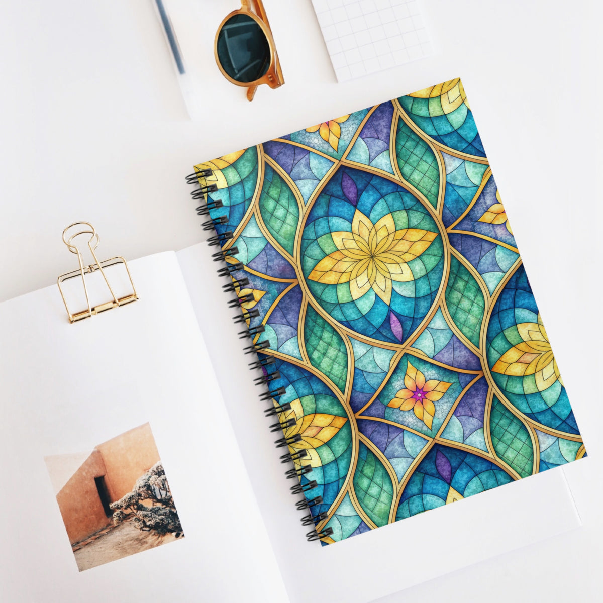 Spiral bound notebook with a stained glass floral design in blue, green, and yellow.