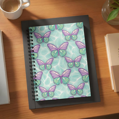Spiral-bound notebook with a purple and green butterfly pattern on a teal background.