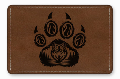 Brown leather patch with white stitched edges featuring an engraved black wolf and paw print design.