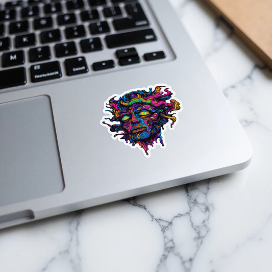 Colorful abstract face sticker with yellow eyes on a laptop.